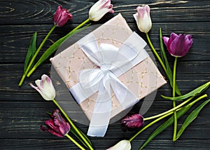 Colorful beautiful pink violet tulips and gift box on gray wooden table. Valentines, spring background.