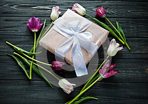 Colorful beautiful pink violet tulips and gift box on gray wooden table. Valentines, spring background.