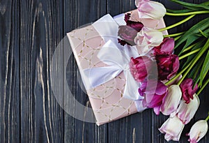 Colorful beautiful pink violet tulips and gift box on gray wooden table. Valentines, spring background.