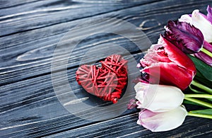 Colorful beautiful pink violet tulips and red heart on gray wooden table. Valentines, spring background. Floral mock up