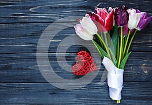 Colorful beautiful pink violet tulips and red heart on gray wooden table. Valentines, spring background. Floral mock up