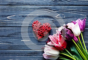 Colorful beautiful pink violet tulips and red heart on gray wooden table. Valentines, spring background. Floral mock up
