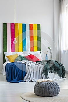 Colorful bed with striped bedhead in a simple and cozy bedroom interior. Real photo