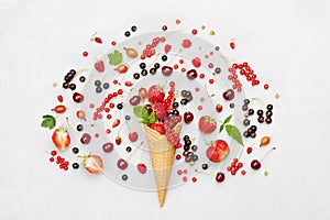 Colorful berries in waffle cone on light background from above. Dietary and healthy dessert. Flat lay styling.