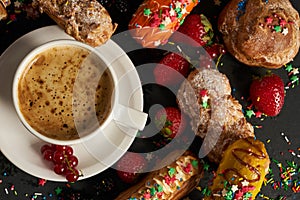 Colorful berry eclairs and coffee cup