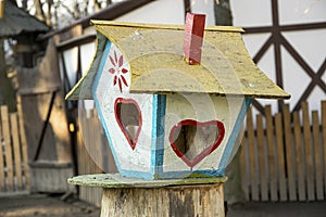 Colorful bird feeder. Creative tree house with food for avian in winter.