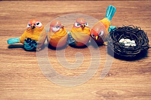 Colorful bird with nest and eggs on wooden background