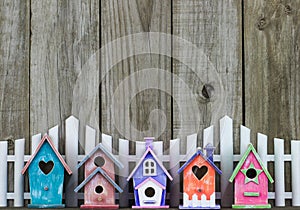 Colorful birdhouses by white picket fence