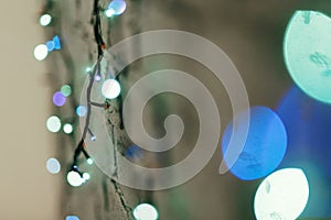 Colorful blue christmas lights hanging on the wall close-up, christmas gift card concept, space for text