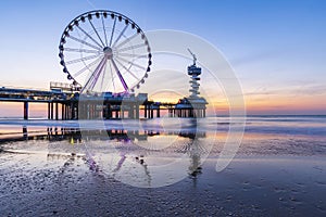 Colorful blue hour sunset on coastline, beach, pier and ferris wheel, Scheveningen, the Hague