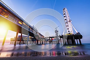 Colorful blue hour sunset on coastline, beach, pier and ferris wheel, Scheveningen, the Hague