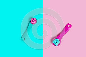 Colorful blue and pink tablets in colored plastic round spoons. Pills, concept of medicine