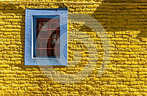 Colorful blue vintage retro window and yellow brick wall of old house building.