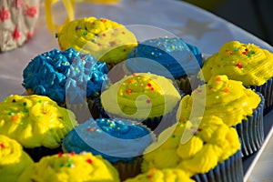 Colorful blue and yellow homemade cupcakes with sprinkles, minion concept party, desserts in blue and yellow color on a table