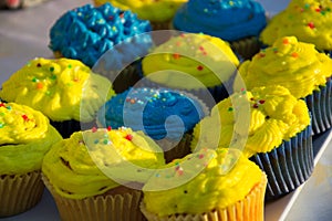 Colorful blue and yellow homemade cupcakes with sprinkles, minion concept party, desserts in blue and yellow color on a table