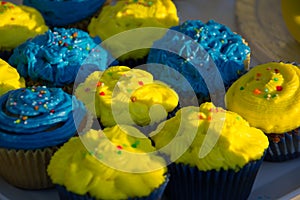 Colorful blue and yellow homemade cupcakes with sprinkles, minion concept party, desserts in blue and yellow color on a table