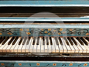 Colorful blue and yellow painted piano with a floral pattern.