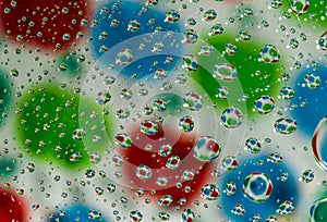 Colorful blurred background with water drops on transparent glass and reflection.
