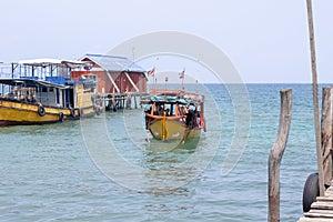 Colorful boat coming to pier of Koh Rong island, Cambodia. Sunny marine travel in tropical island.