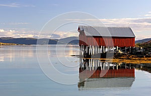 Colorful boat house reflected in the fjord waters