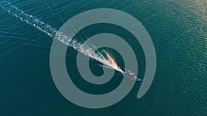 Colorful boat sailing on clean blue Venezuela's sea surface. Aerial drone shot over speed boat with small waves in