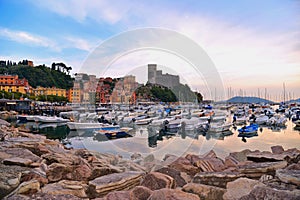 Colorful boats and seascape with old castle and blue cloudy sky with sunset in Lerici in Liguria, Italy