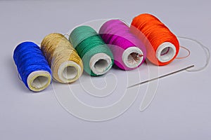 Colorful bobbins of thread with needle