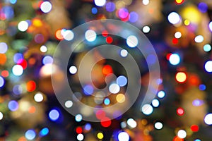 Colorful bokeh garland lights and Christmas tree toys defocused abstract blurred background.