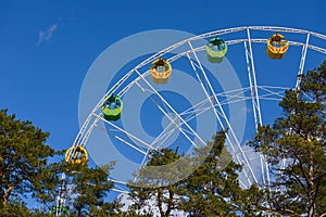 Colorful booths on a Ferris wheel against a clear blue cloudless sky. Ferris Wheel is in the park