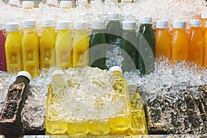 Colorful bottles with fresh fruit and vegetable juice in ice at thai market. Lealthy lifestyle, travel concept