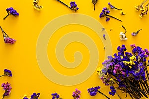 Colorful bouquet of dried autumn flowers lying on yellow paper background. Copy space. Flat lay.