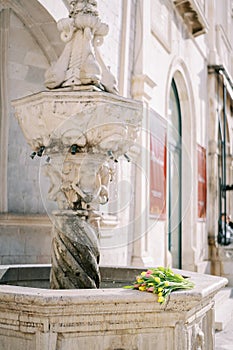 Colorful bouquet of flowers lies on Onofrio small marble fountain. Dubrovnik, Croatia