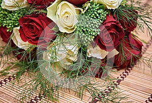 Colorful bouquet of white and red roses on bege bamboo straw mat, close up