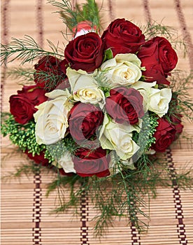 Colorful bouquet of white and red roses on bege bamboo straw mat, close up