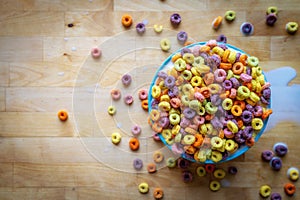 Colourful Bowl of Cereal Spilling Over Wooden Table Top Flat Lay