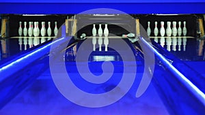 Colorful bowling alley. Bowling ball knocks down 7 pins. Ball is rolling