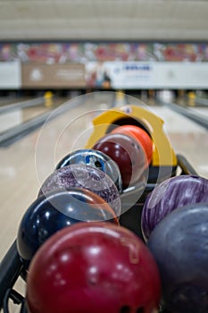 Colorful bowling balls in return machine at bowling alley.