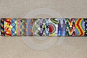 Colorful braided friendship bracelets handmade of thread on stand for sale isolated on beige background with copy space