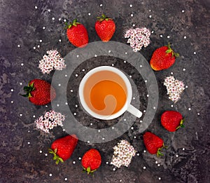 Colorful bright composition of cup of tea, fresh strawberries and wild flowers. Flat lay