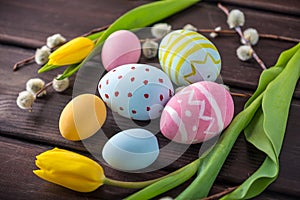 Colorful Easter eggs with yellow Tulip hand painted on a dark wooden background. Holiday spring card