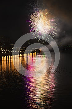 Colorful bright fireworks, salute of various colors in night sky with reflection in the lake. Abstract holiday