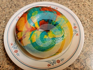 colorful bright rainbow bagel with many colors on plate