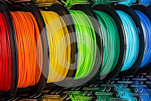 Colorful bright row of spool 3d printer filament black metal background