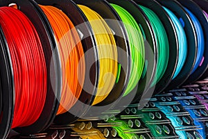 Colorful bright row of spool 3d printer filament black metal background