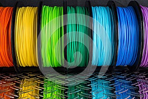 Colorful bright row of spool 3d printer filament black metal background