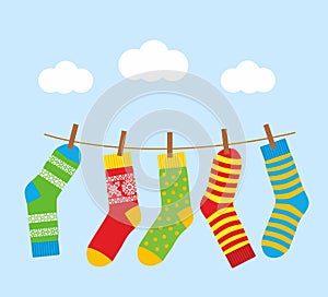 Colorful bright socks on a rope with clothespins against a background of sky and clouds.