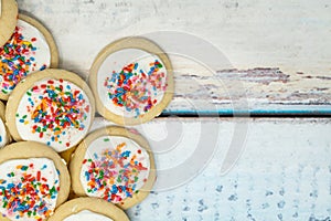 Vanilla white frosted homemade sugar cookies piled on a blue woo photo