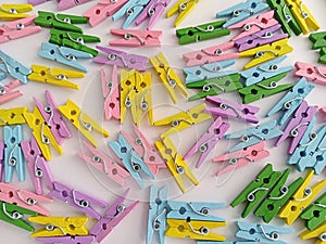 Colorful bright wooden clothes pins scattered on a white background