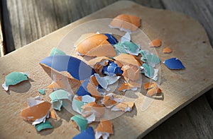 Colorful broken Easter eggshells on a wooden cutting board