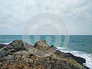 Brown rocks on the blue sea shore in cloudy day